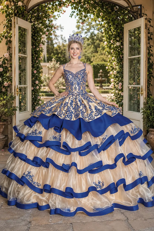Front view of a gold and royal blue quinceanera dress with embroidered bodice and tiered ribbon-trimmed sheer skirt