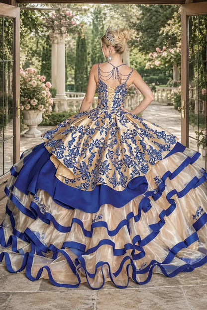 Back view of a gold and royal blue quinceanera dress with lace-up corset, embroidered bodice, and tiered ribbon-trimmed sheer skirt