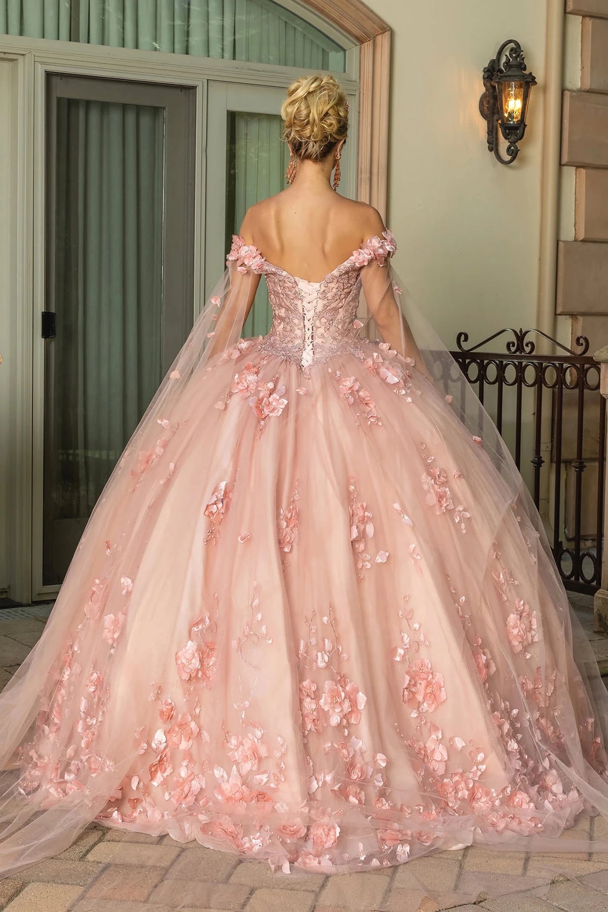 Back view of a Rose Gold quinceañera gown showing lace-up back, cap sleeves, and floral appliqués