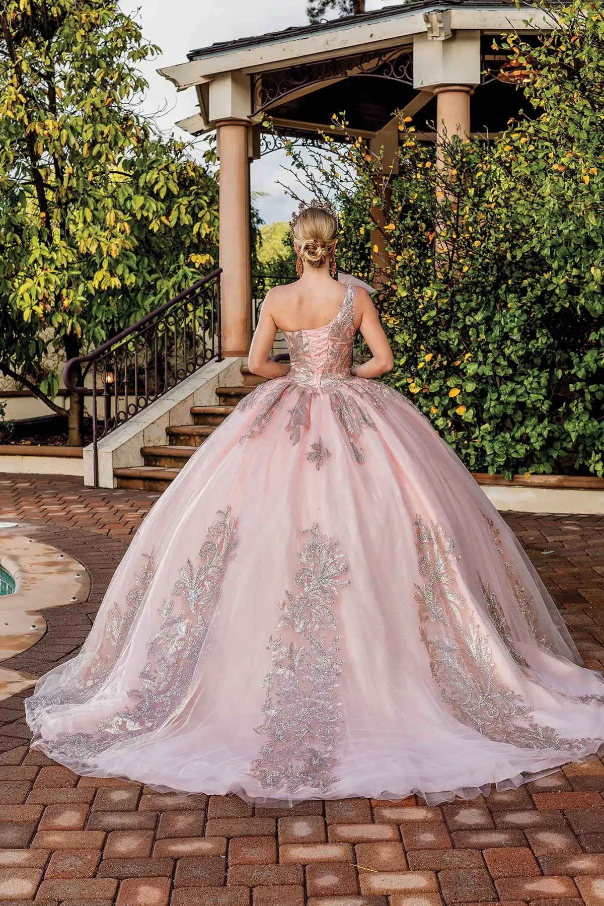 Back view of a Rose Gold quinceañera gown showing lace-up back and flowing train