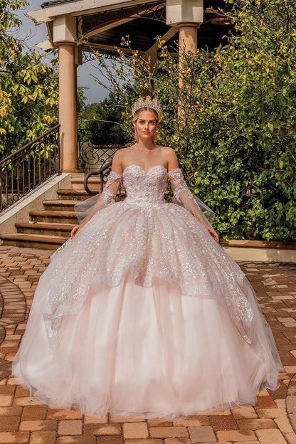 Front view of a woman wearing blush quinceañera dress with sweetheart strapless corset, glitter tulle skirt and detachable sleeves