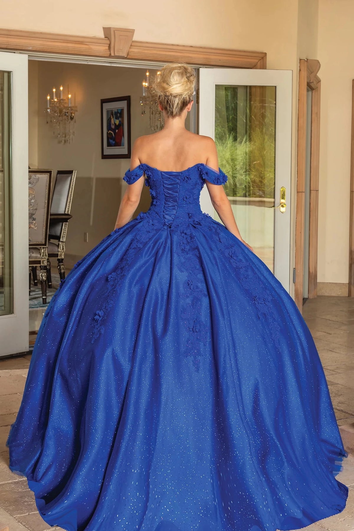 Back view of a Royal Blue quinceañera gown showing lace-up back, glitter tulle skirt, and floral appliqués