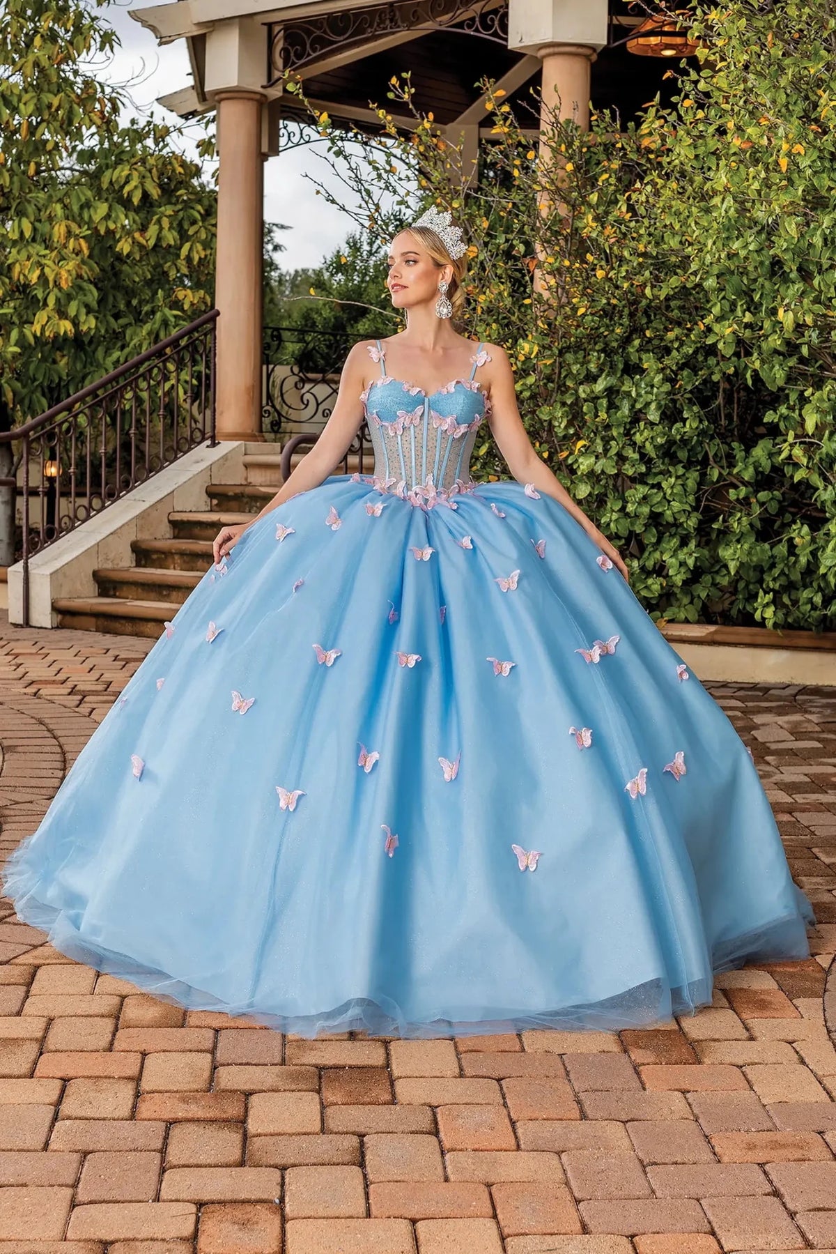 Front view of a Bahama Blue quinceañera gown with corset bodice and butterfly appliqués