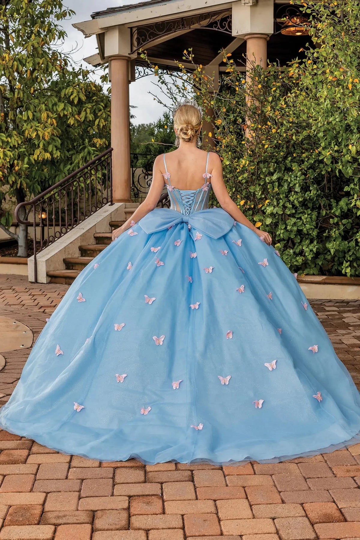 Back view of a Bahama Blue quinceañera gown showing lace-up back and butterfly appliqués