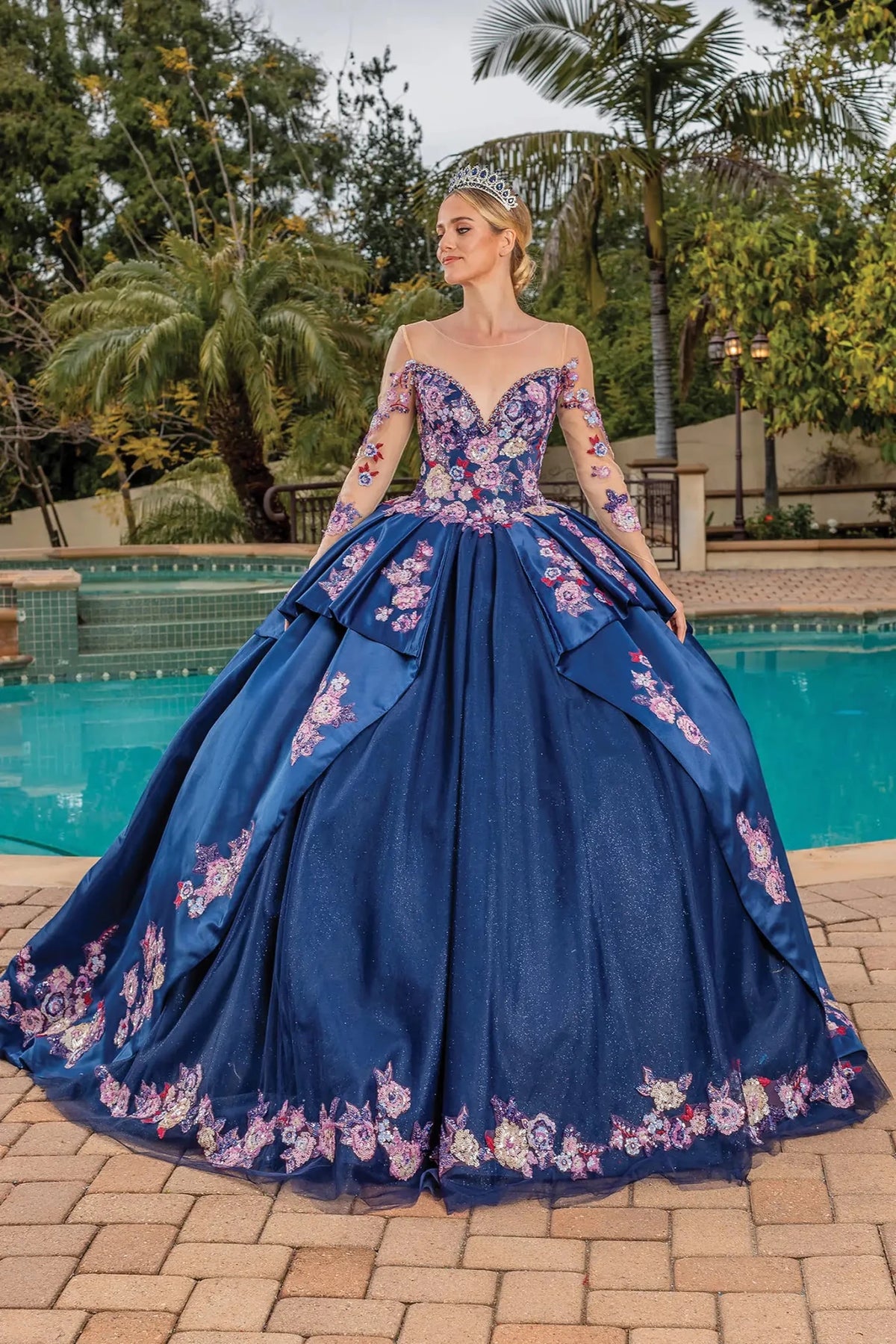 Front view of a Navy quinceañera gown with sheer long sleeves and floral appliqués