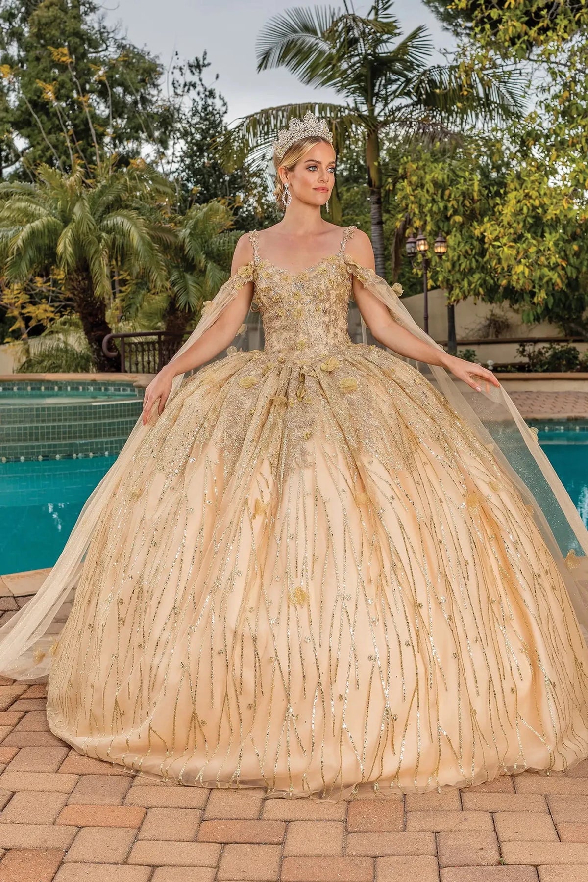 Front view of a Gold quinceañera gown with sheer sleeves, embroidered bodice, embroidered appliqués, and glitter tulle skirt