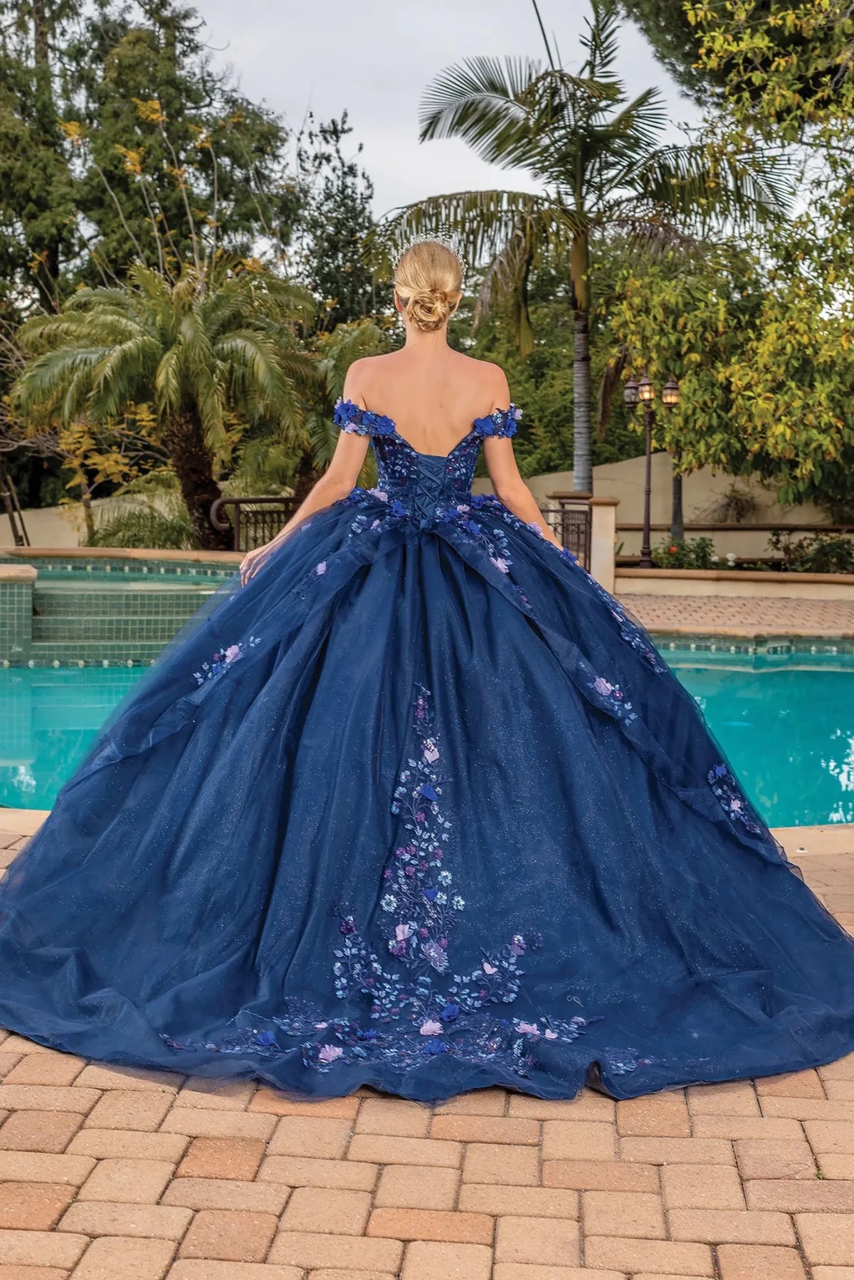 Back view of a Navy quinceañera gown showing lace-up back and embroidered tulle skirt