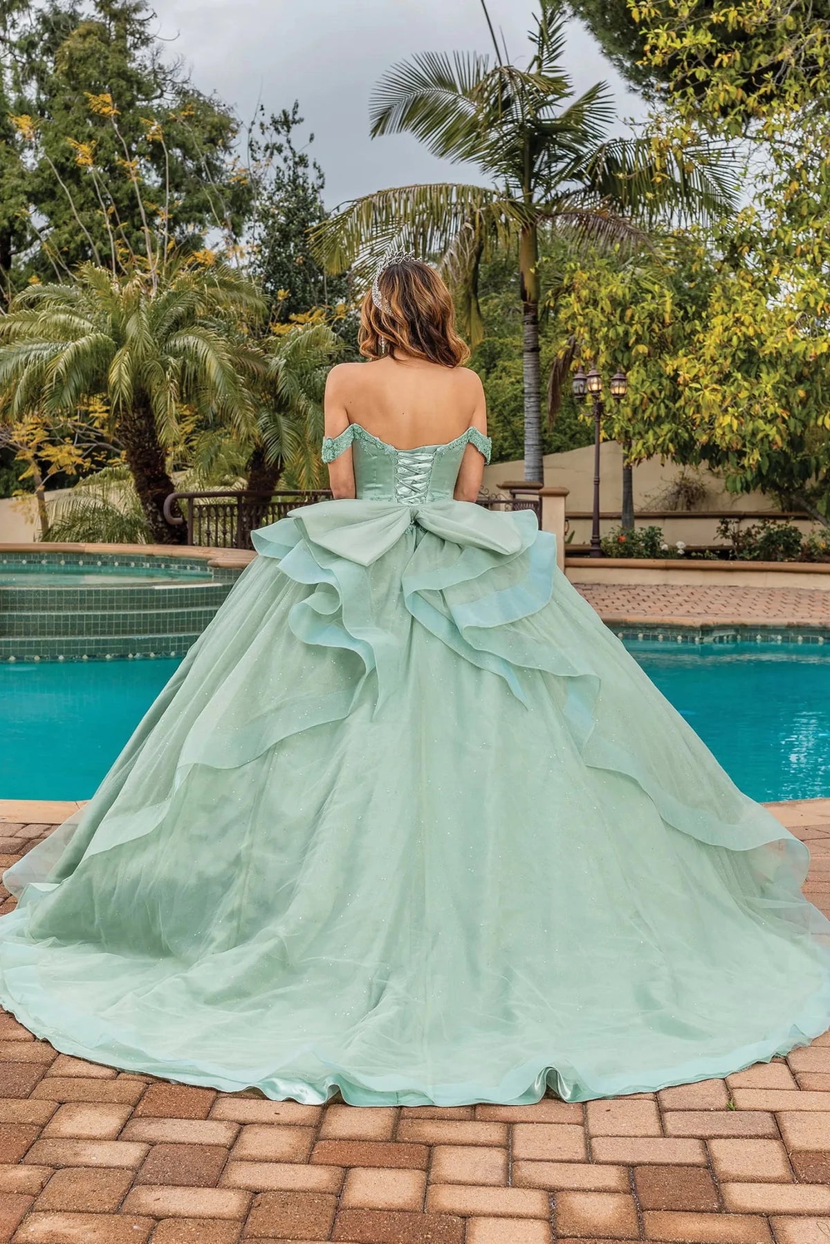 Back view of a Sage quinceañera gown showing lace-up back and ruffled layered skirt