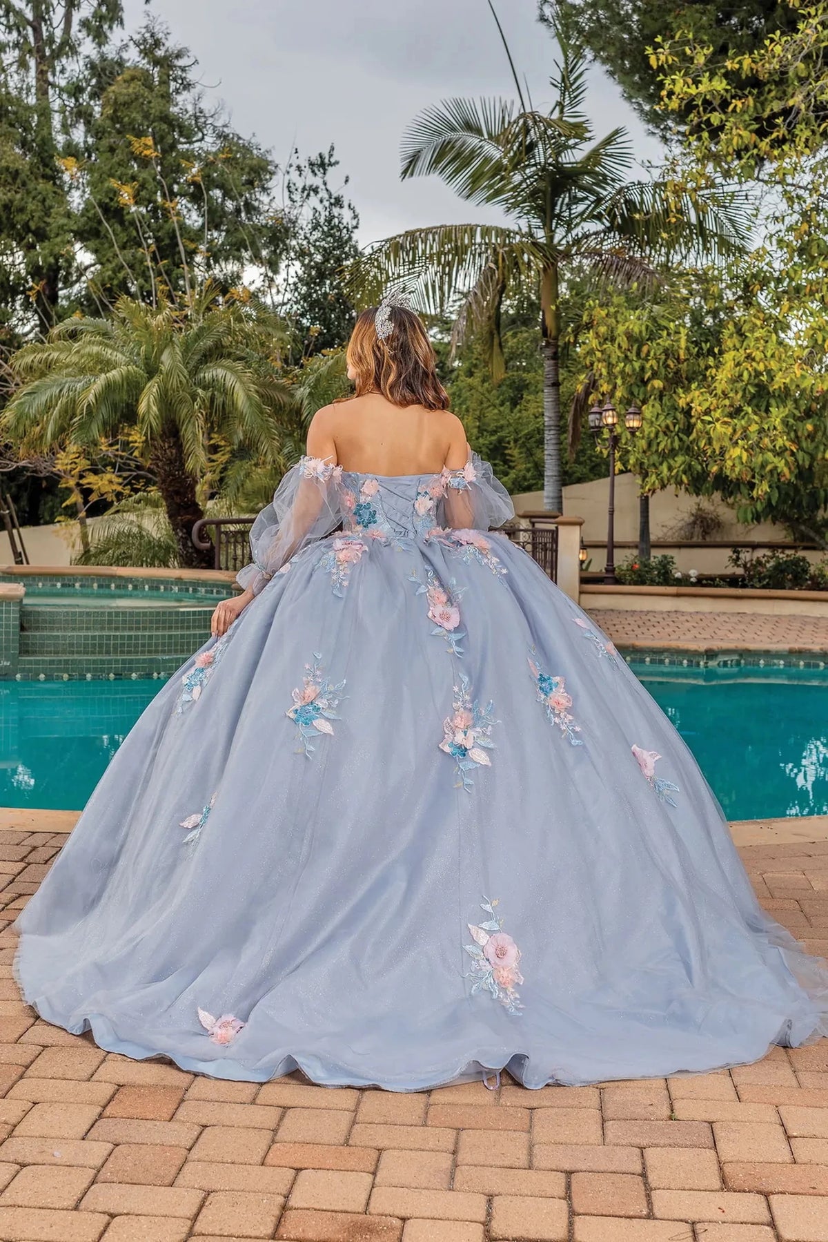 Back view of a Silver quinceañera gown showing lace-up back, sheer sleeves, and voluminous full skirt