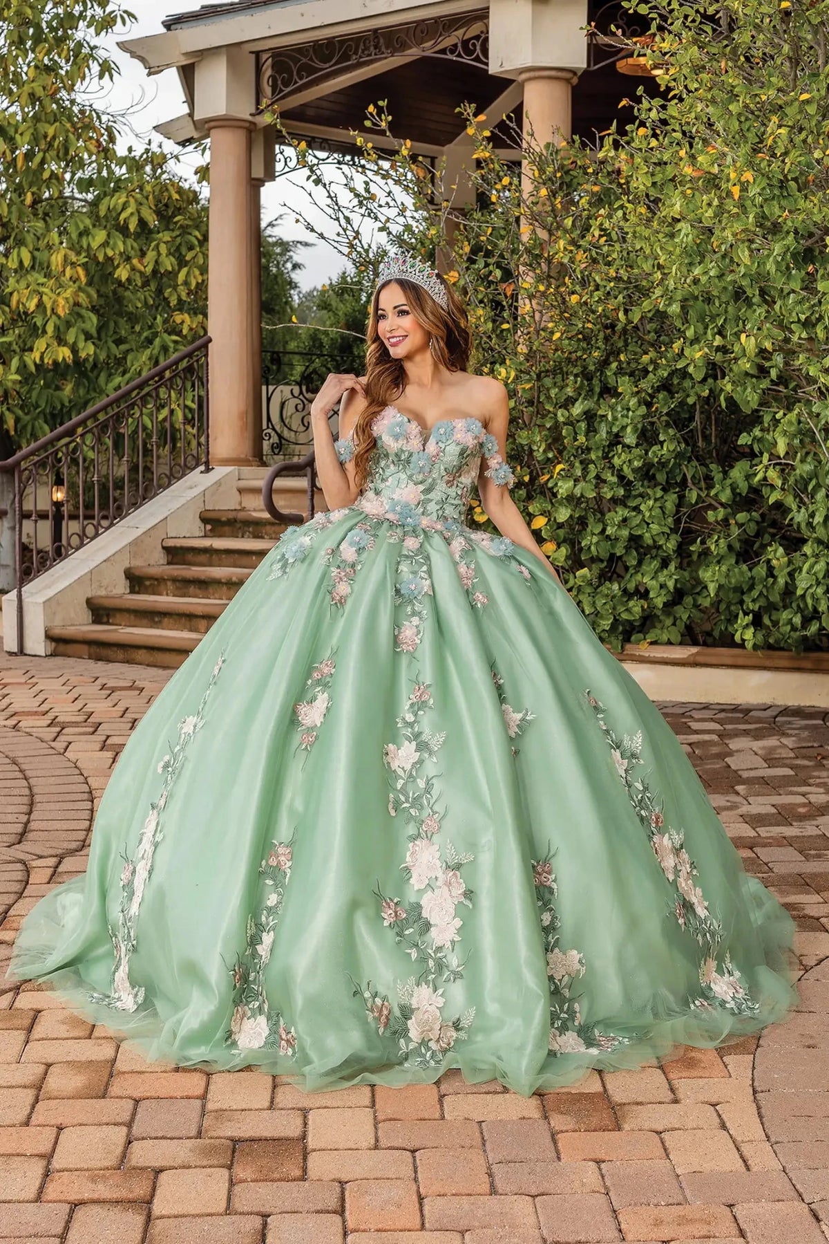 Front view of a Sage quinceañera gown with off-the-shoulder neckline, corset bodice, and floral appliqués