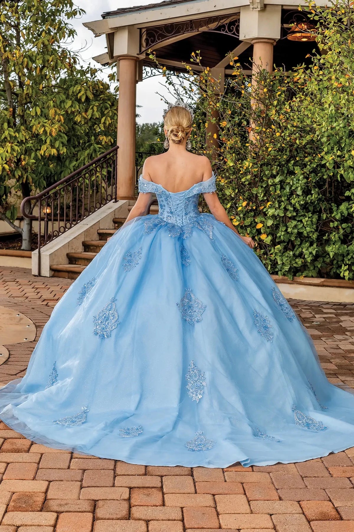 Back view of a Bahama Blue quinceañera gown showing lace-up back, full tulle skirt, and lace appliqués