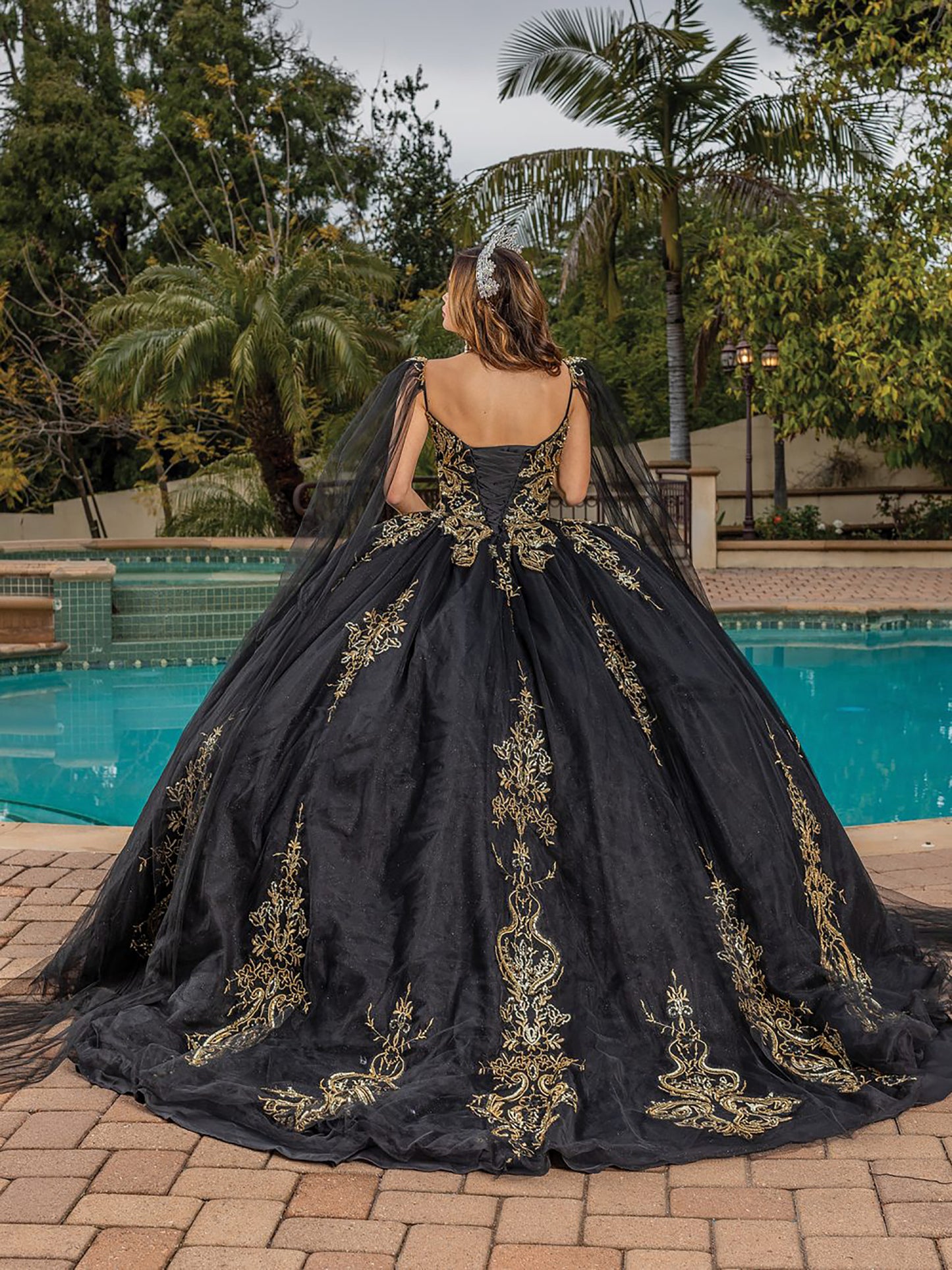 Quinceanera | Black Opulent Embroidered Gold Coiled Off-Shoulder Glittered tulle Ballgown with Dramatic Train - back view of woman wearing dress