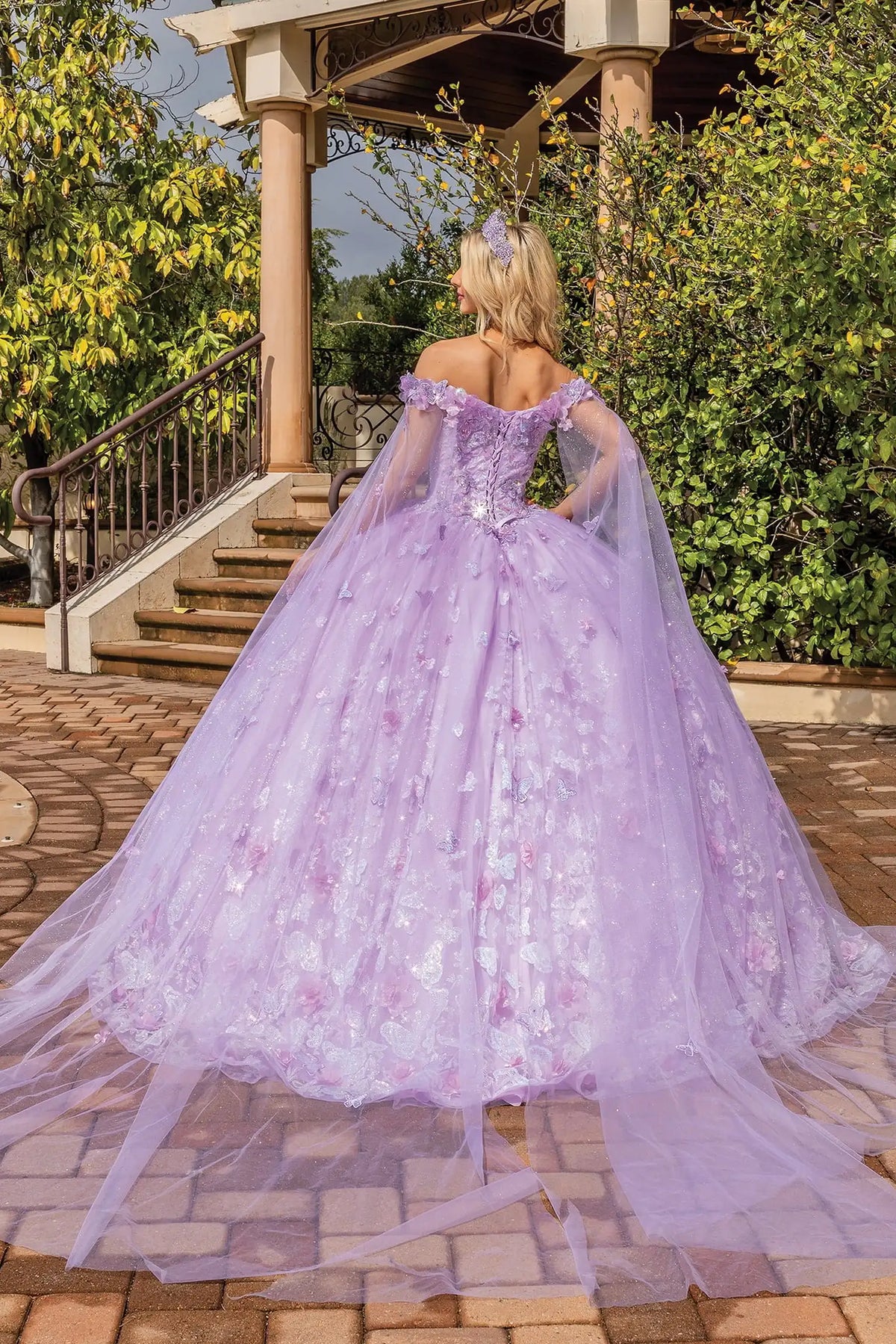 Rear full-length view of a Lilac quinceañera gown showing lace-up back and floral appliqués
