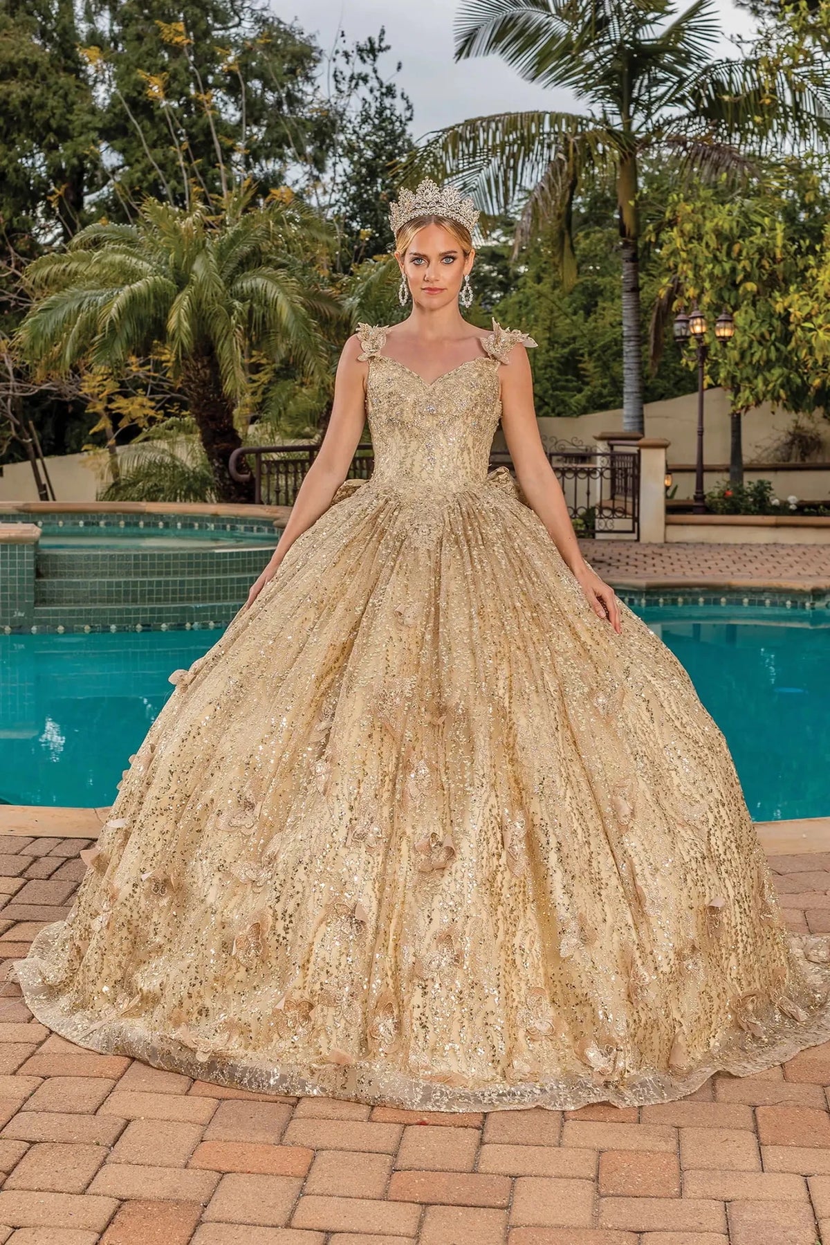 Front view of a Gold quinceañera gown with off-the-shoulder neckline, sheer long sleeves, embellished bodice, and sequined lace