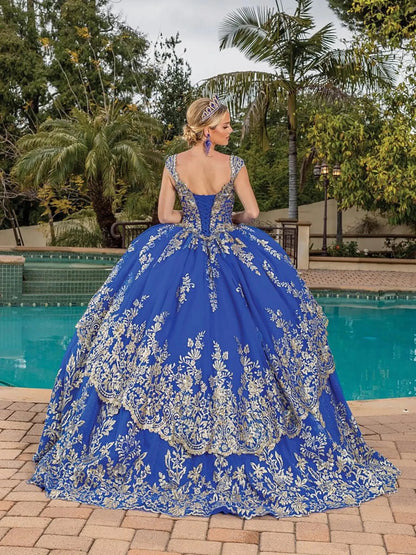 Back view of royal blue quinceañera ball gown showcasing deep V-back corset, ornate gold embroidery, voluminous ball gown skirt, and elegant silhouette photographed outdoors by a pool