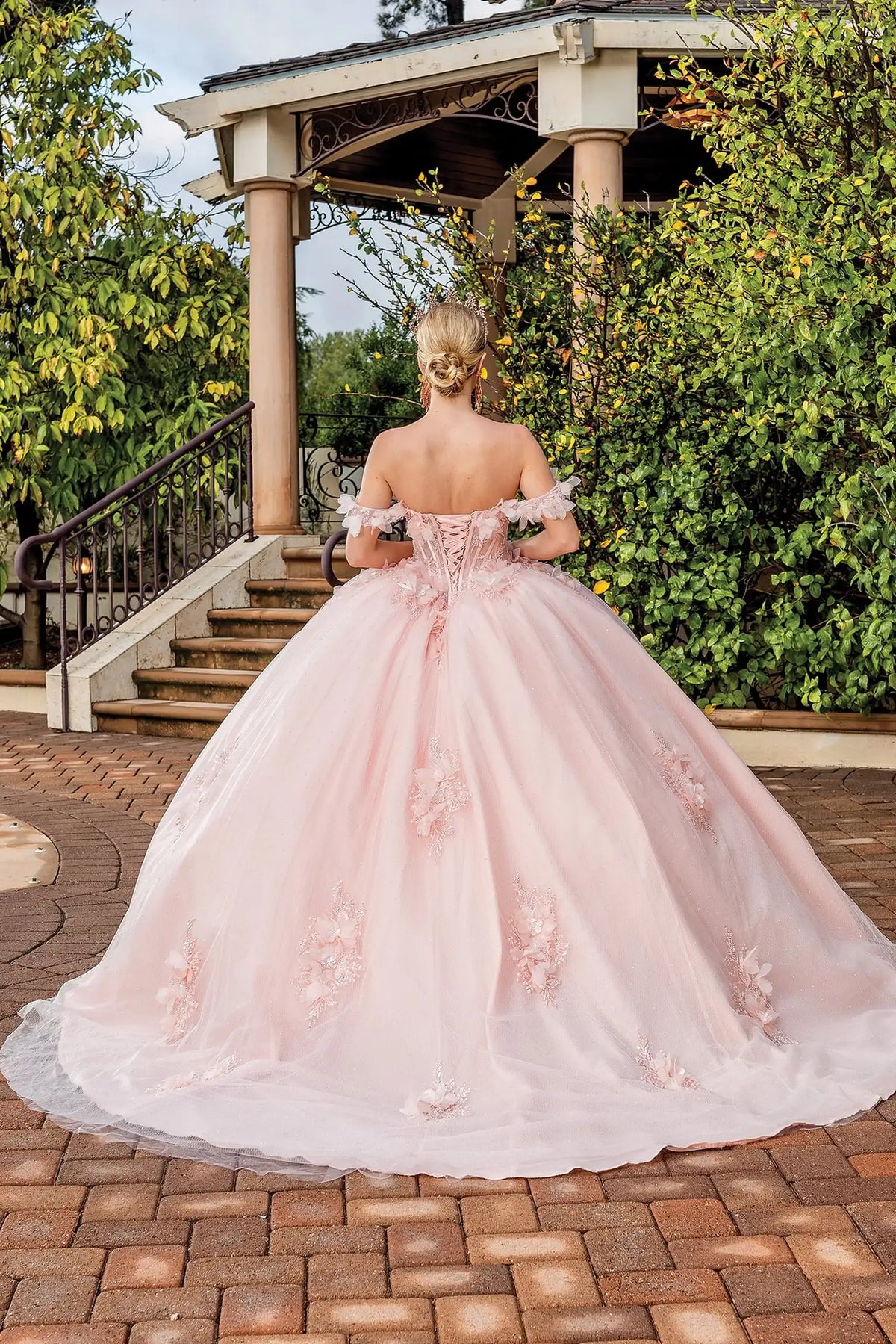 Back angle of a Blush quinceañera gown showing lace-up back and floral appliqués