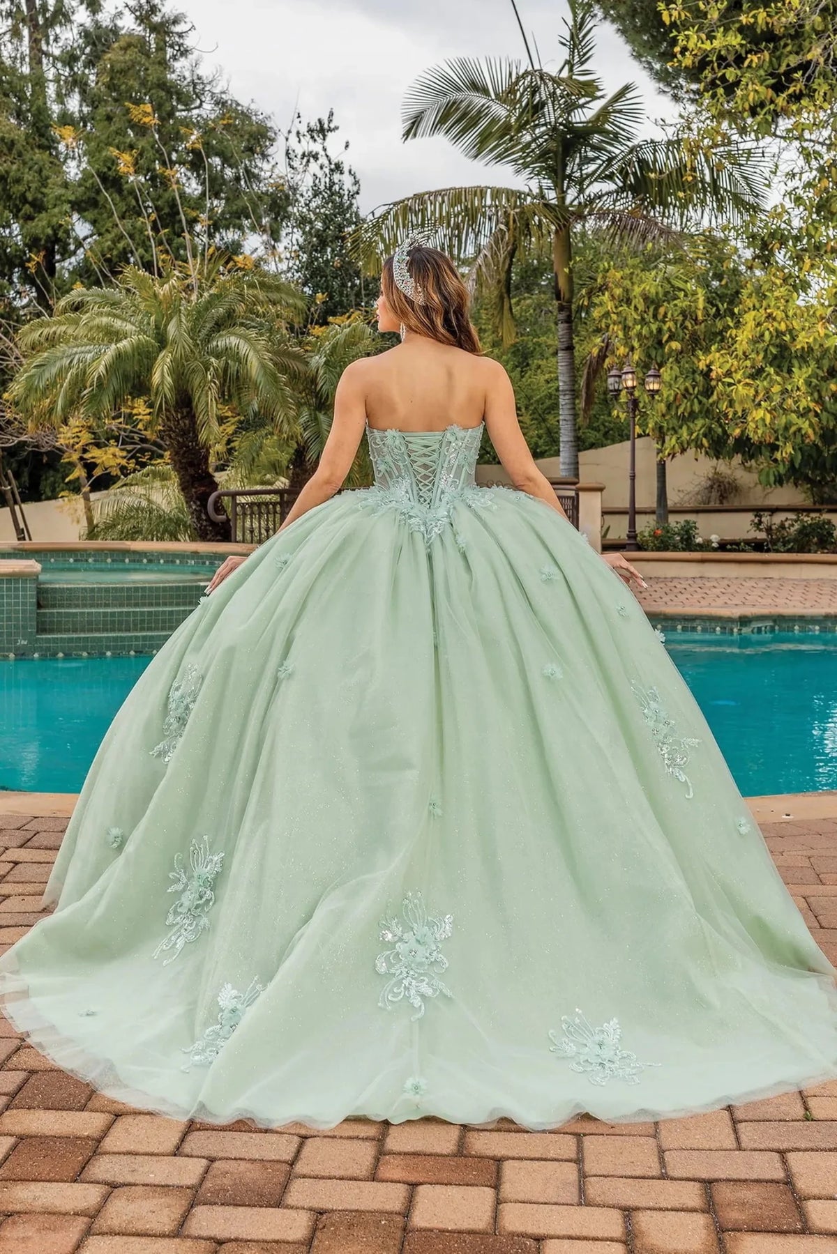 Back view of a Sage quinceañera gown showing lace-up back and embroidered appliqués