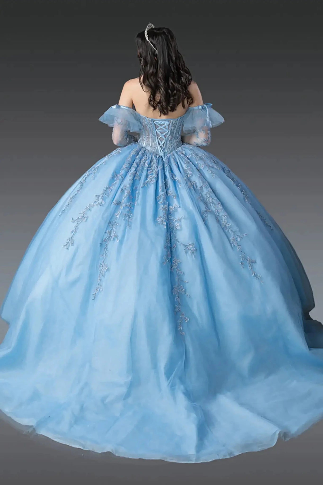 Back view of sky blue quinceañera ball gown featuring lace-up corset back, off-the-shoulder tulle sleeves, embroidered appliqués, and full flowing tulle skirt