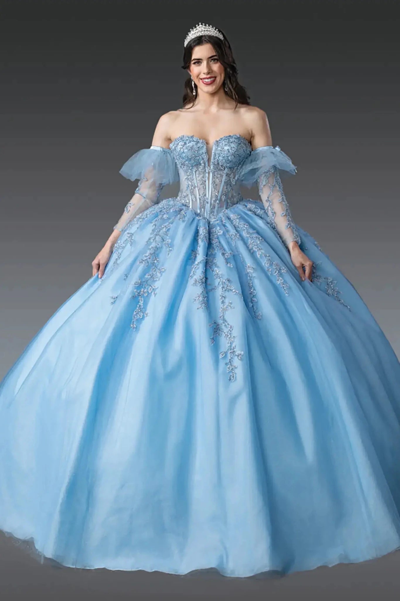 Front view of sky blue quinceañera ball gown with sheer corset bodice, off-the-shoulder tulle sleeves, lace appliqués, and voluminous tulle skirt.