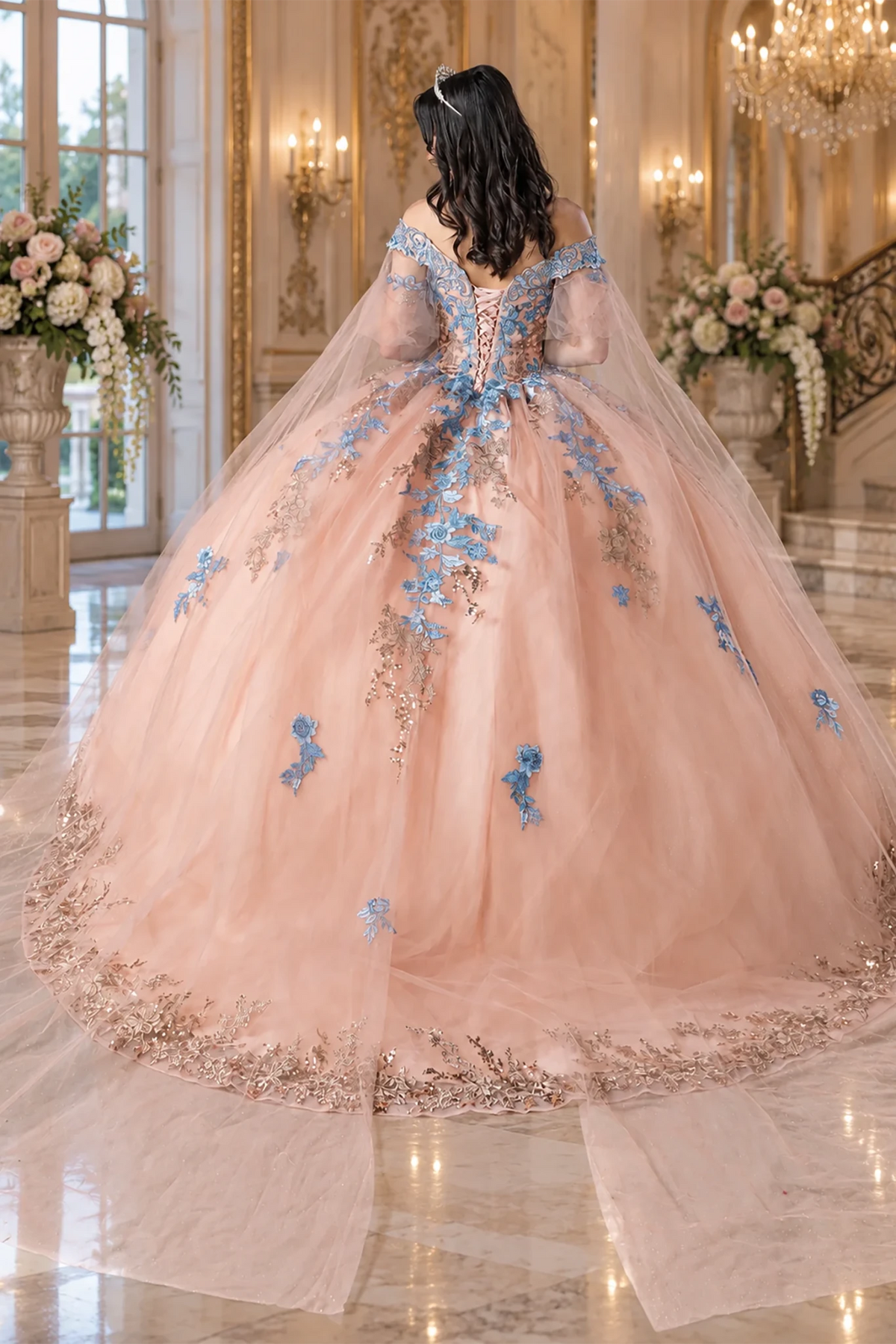 voluminous peach tulle quince ball gown with blue floral embroidery, a lace-up back, and a long sheer veil.