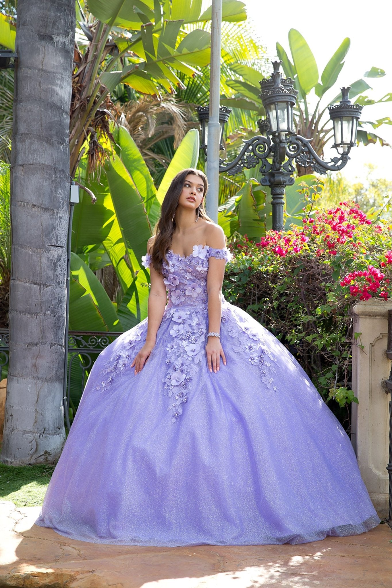 Girl in a Lilac floral quince dress standing and looking at a tree in a garden setting