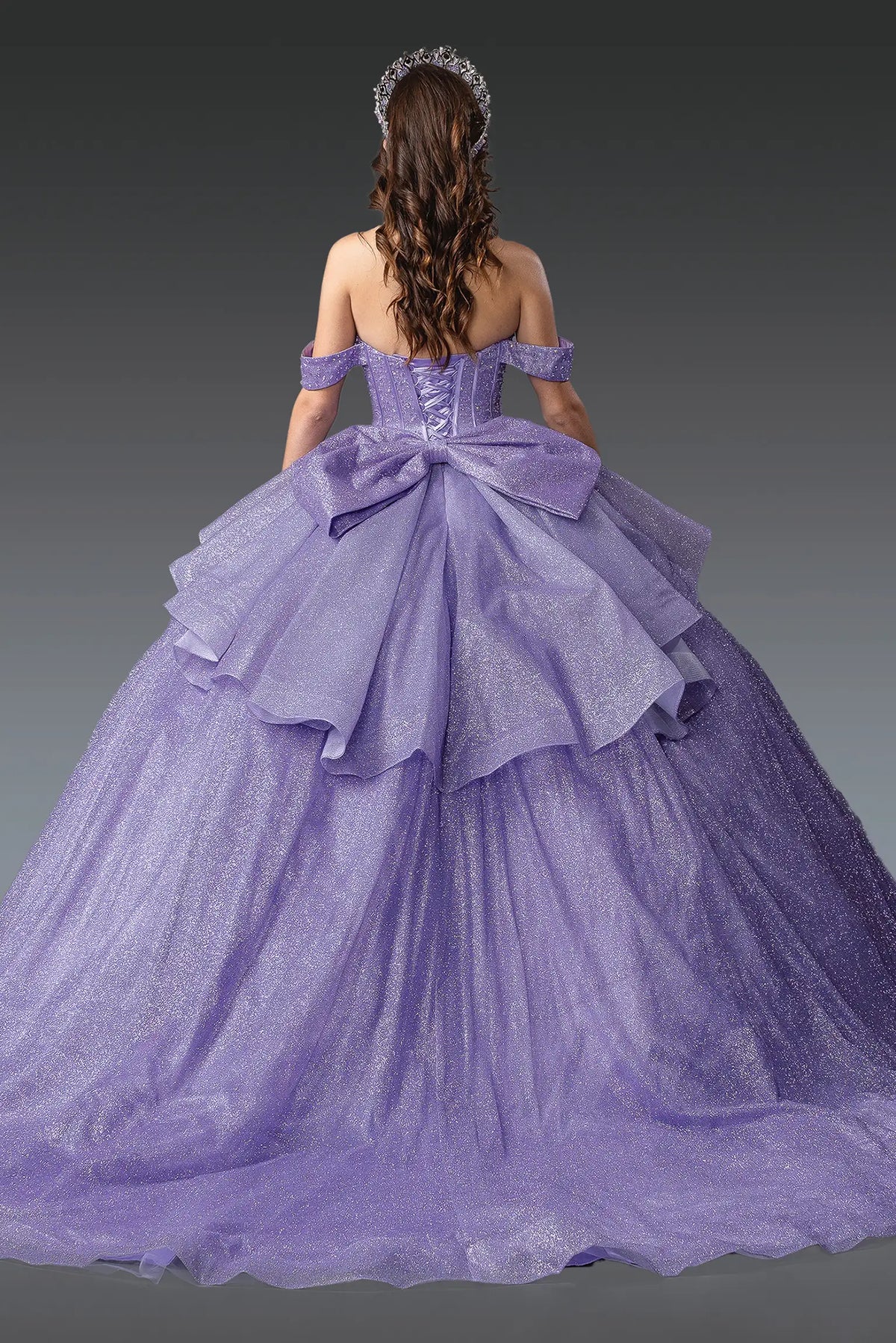 Revealing corset lacing beneath an oversized back bow, this Lilac quinceañera ball gown is shown from the back.