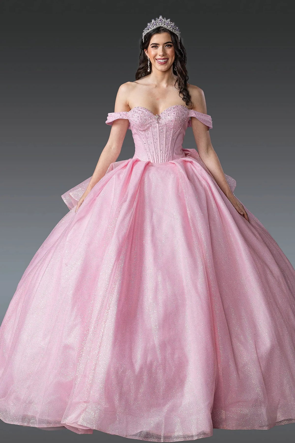 Showing a structured sweetheart bodice and glitter tulle skirt, this Pink quinceañera ball gown is shown in full view.