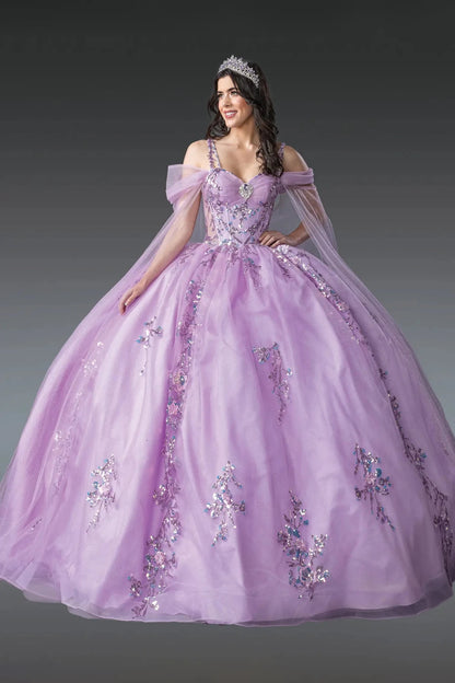 Woman standing front-facing in lilac quinceañera ball gown with sheer puffed sleeves, fitted bodice, embellished floral appliqués, and voluminous layered tulle skirt