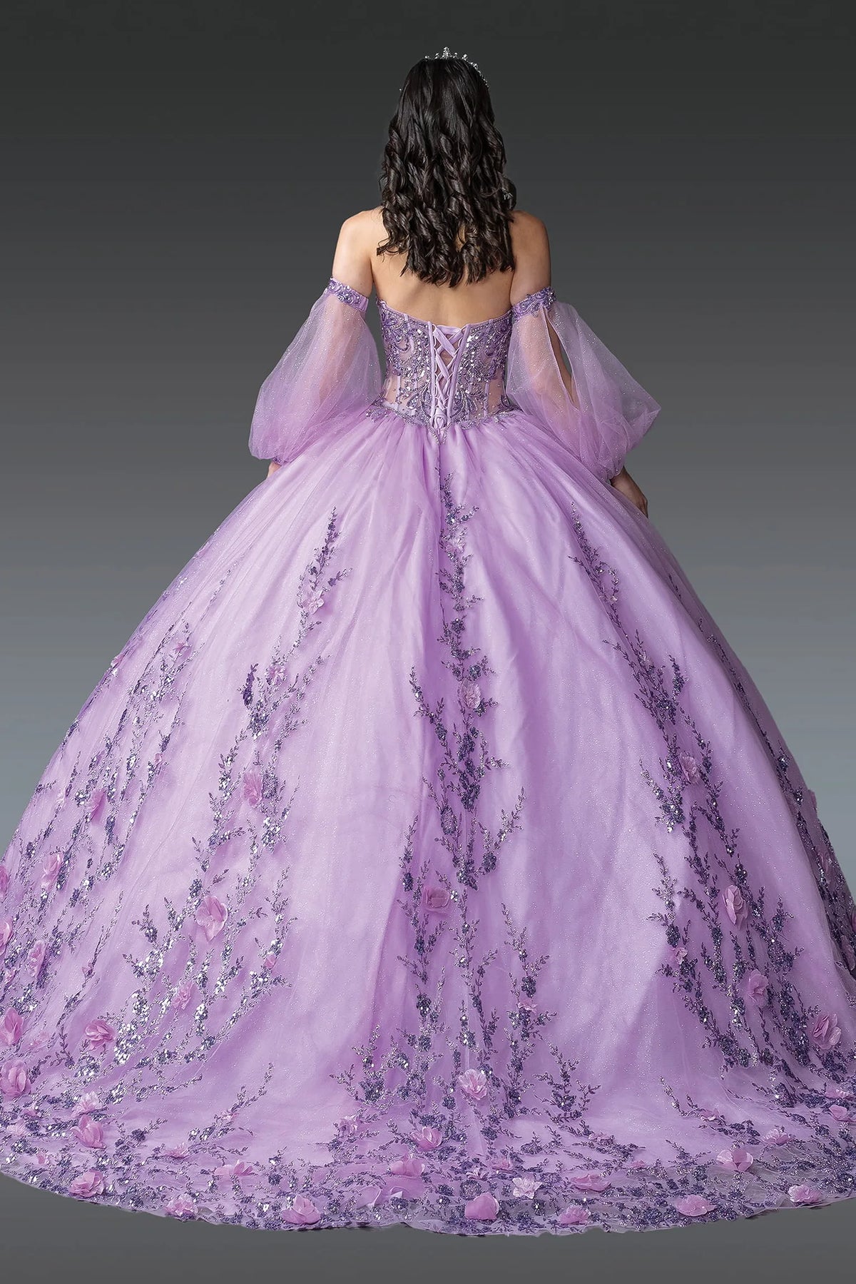 Back view of a Lilac quinceañera gown showing lace-up back, puff sleeves, and floral appliqués