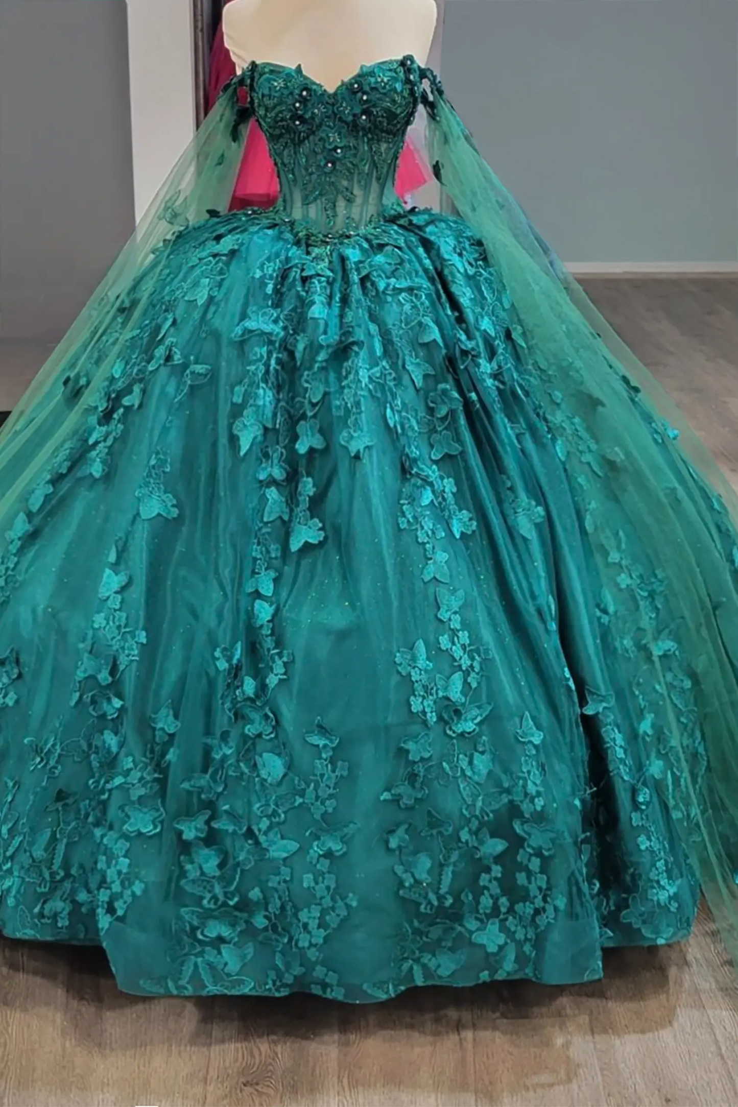 hunter green quinceanera dress with beaded bodice, floral embroidery, butterfly appliques, and sheer long sleeves cape