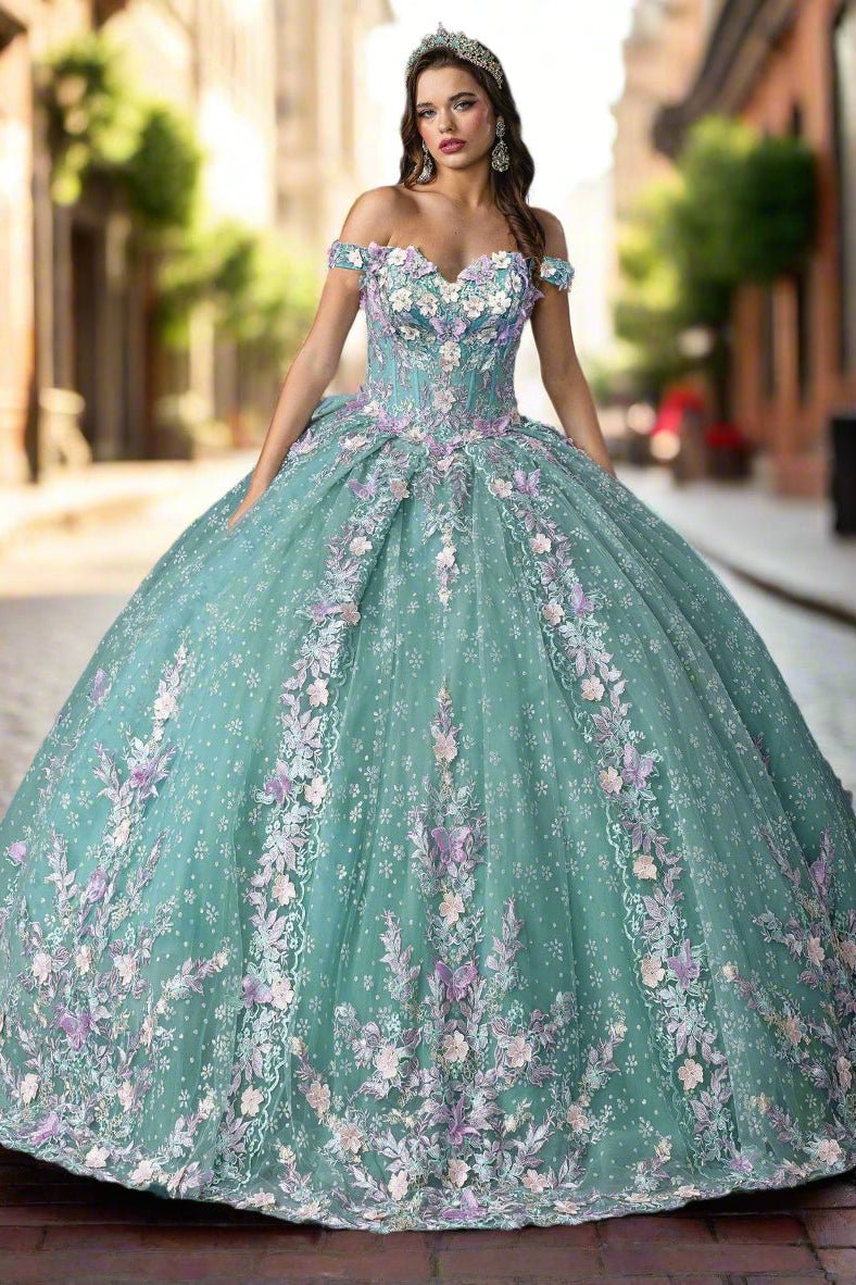 Woman standing front-facing in sage quinceañera ball gown with strapless bodice, embroidered floral accents, and layered ruffled voluminous skirt
