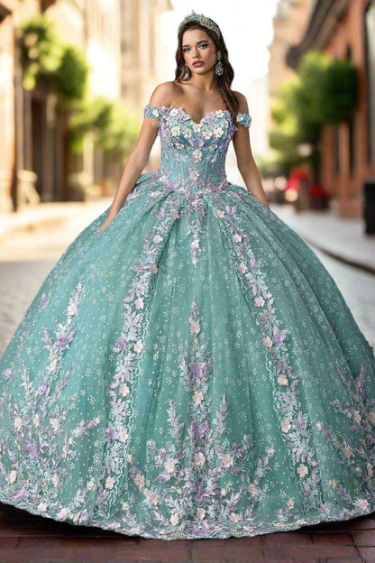 Woman standing front-facing in sage quinceañera ball gown with strapless bodice, embroidered floral accents, and layered ruffled voluminous skirt