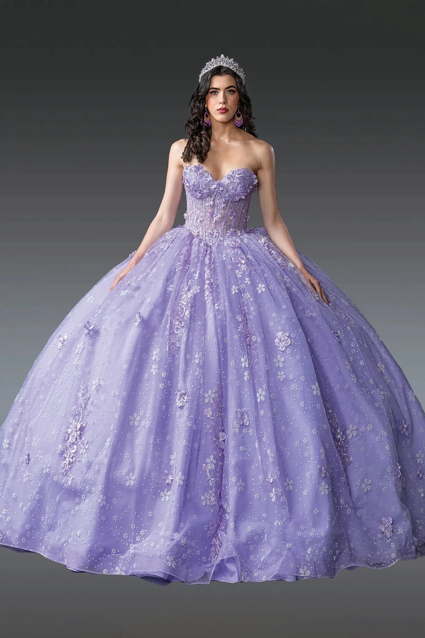 A strapless lilac Quinceañera dress with 3D floral appliqués and a sparkling ball gown skirt, featuring a sweetheart neckline and lace up front.