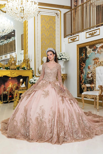 Woman standing front-facing in elegant rose gold quinceañera ball gown with lace overlay, sparkling accents, sheer long sleeves, and voluminous skirt