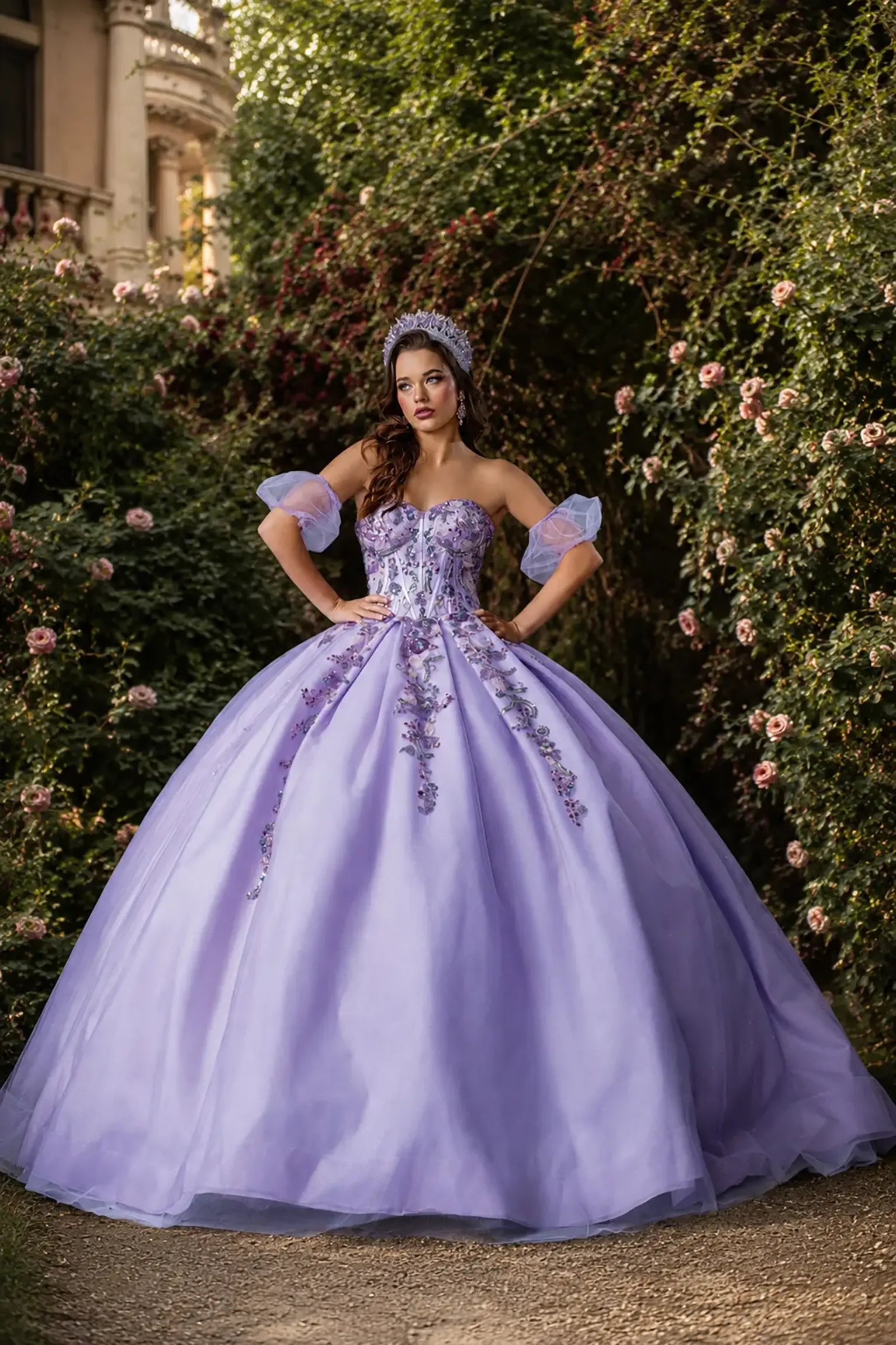 Front view of a lilac quinceanera dress with floral appliques, glittered fabric, detachable puff sleeves, and layered tulle skirt