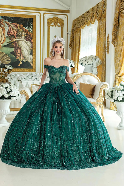 Woman standing front-facing in hunter green quinceañera ball gown with off-shoulder sleeves, sequined overlay, beaded bodice, and shimmering layered skirt