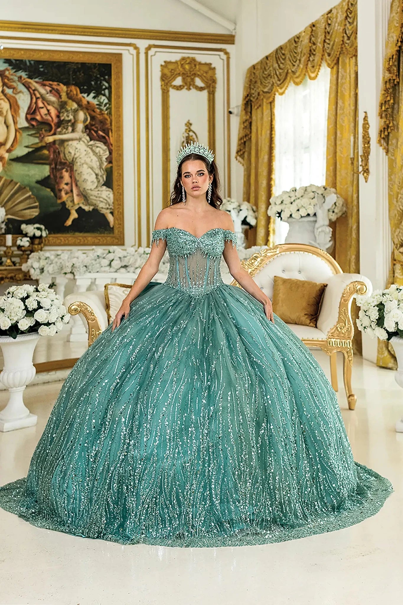 Woman standing front-facing in sage quinceañera ball gown with strapless bodice, embroidered floral accents, and layered ruffled voluminous skirt