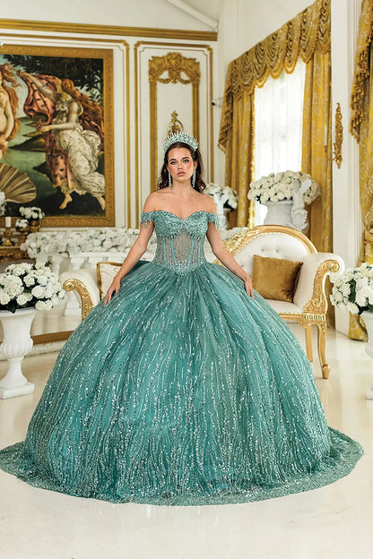 Woman standing front-facing in sage quinceañera ball gown with strapless bodice, embroidered floral accents, and layered ruffled voluminous skirt