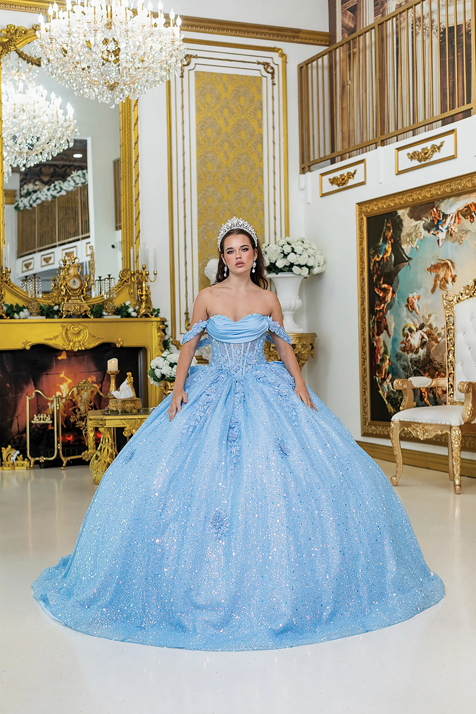 Front view of a woman wearing bahama blue quinceañera dress featuring off-shoulder neckline, ruched bodice, 3D floral appliqué, and glitter tulle skirt