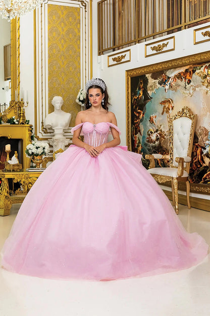 Woman standing front-facing in pink strapless quinceañera ball gown with off-shoulder sleeves, sheer corset bodice, and voluminous sparkling tulle skirt