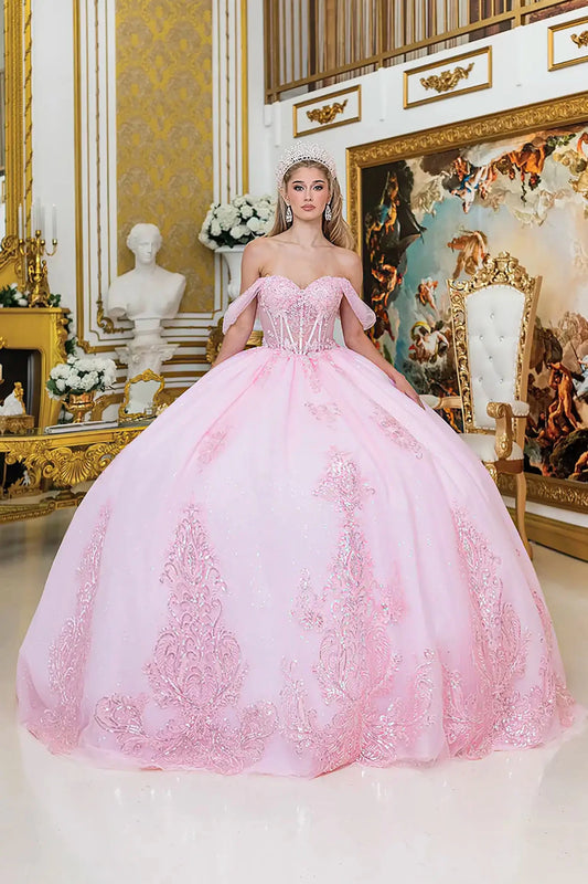 Woman in a pink ball gown with off shoulder standing in an ornate room with gold accents and decorative elements.
