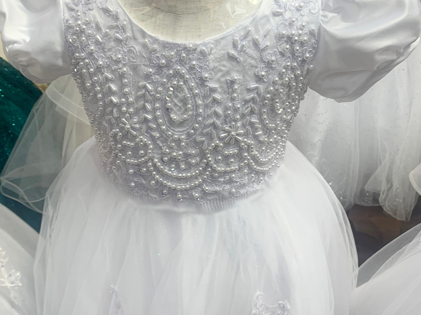 zoomed in front view of communion dress showing pattern and pearls.