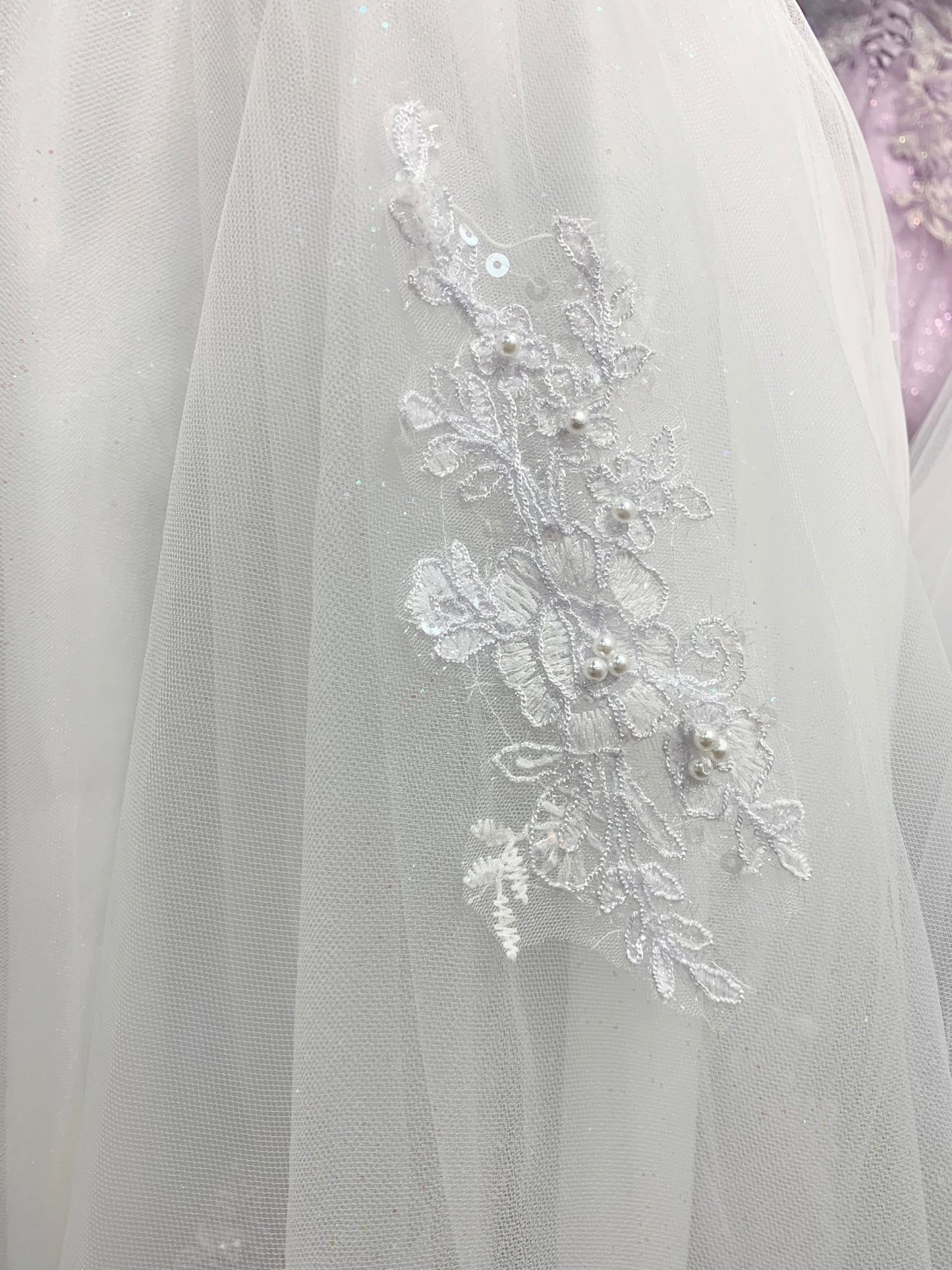 zoomed in view of skirt showing detailed pattern with pearls. Communion dress.