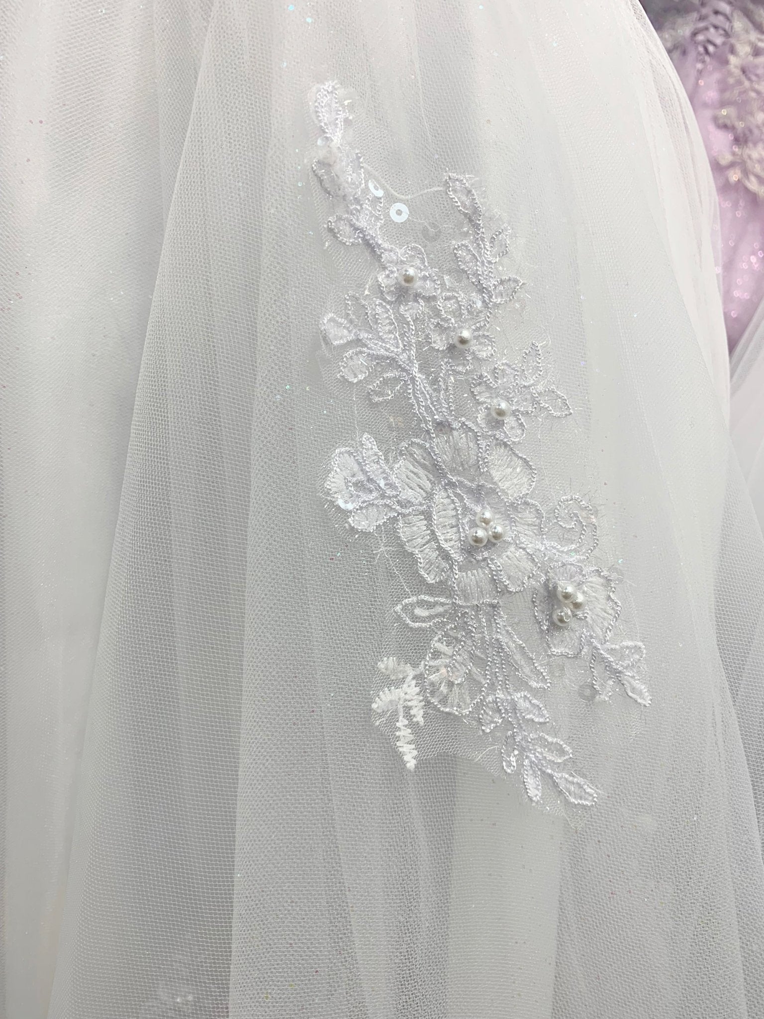 zoomed in view of skirt showing detailed pattern with pearls. Communion dress.