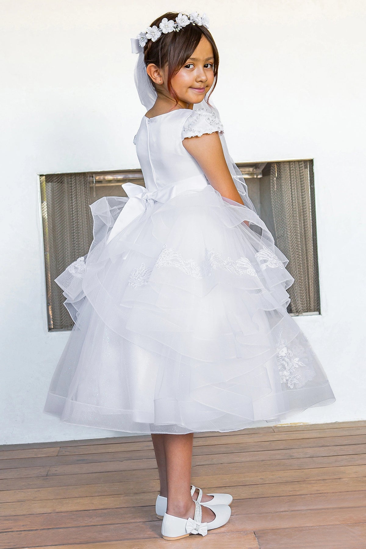 Back bow sits above ruffled skirt layers on this White communion dress.