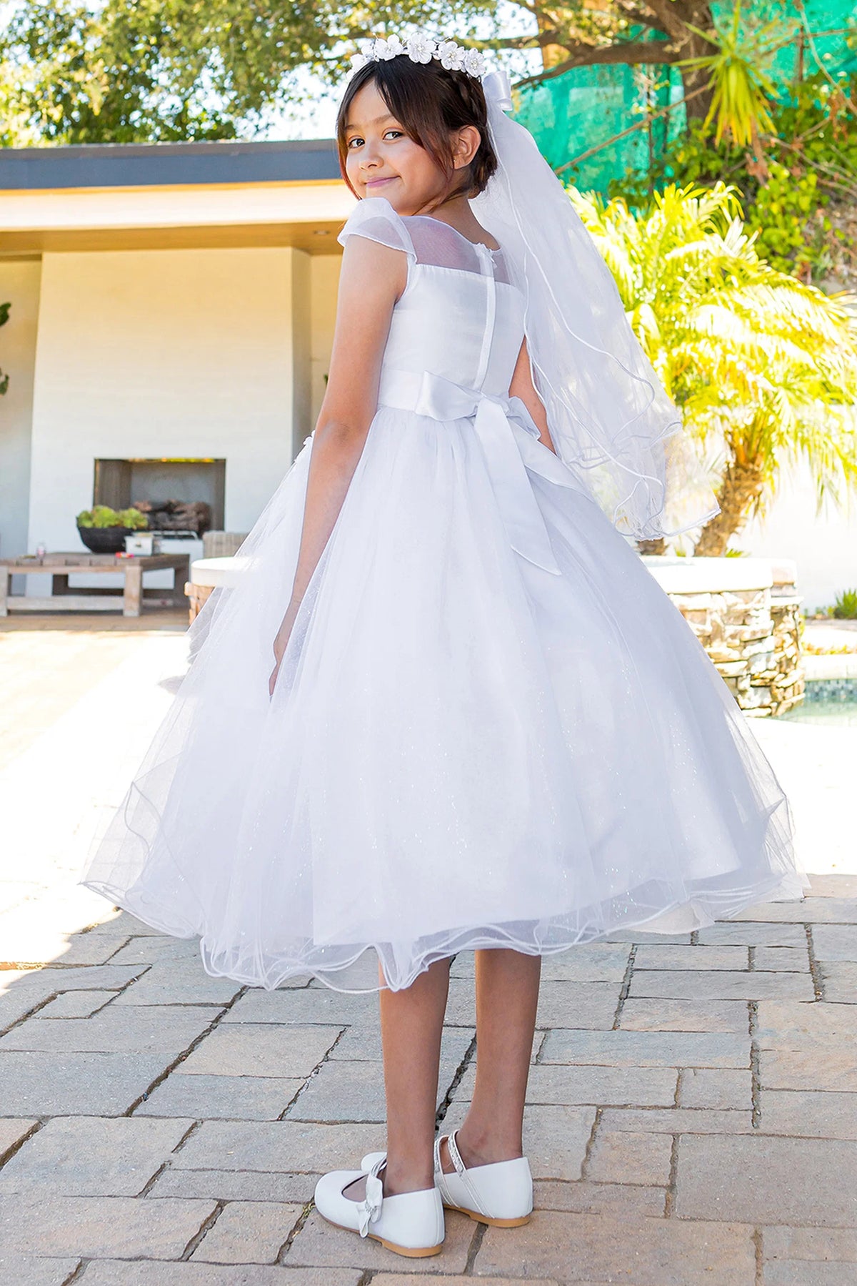 Sheer floral upper back and a satin bow finish the White communion dress.