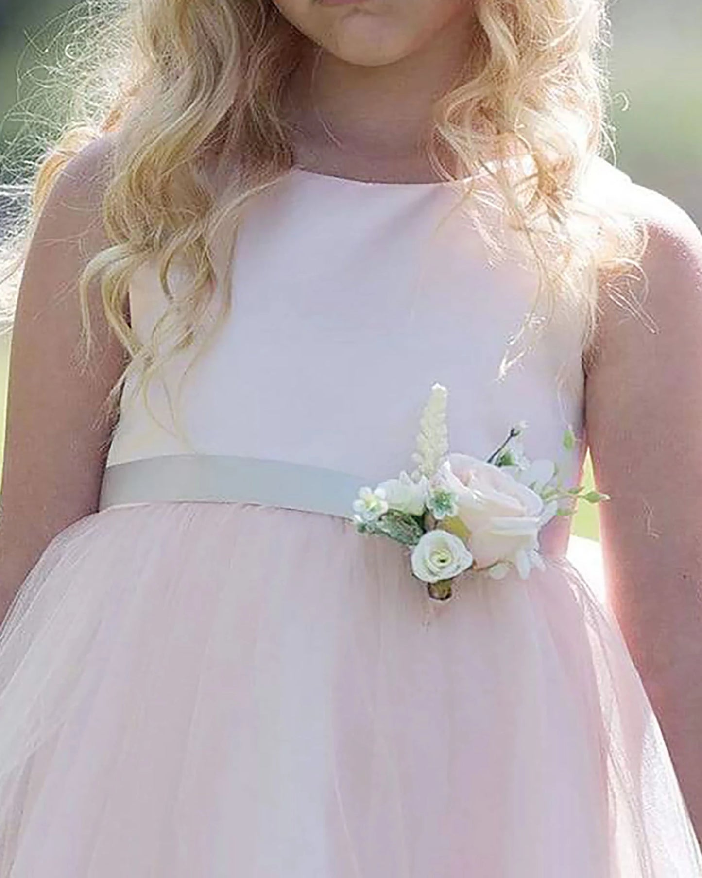 A light pink flower girl dress with a floral corsage.