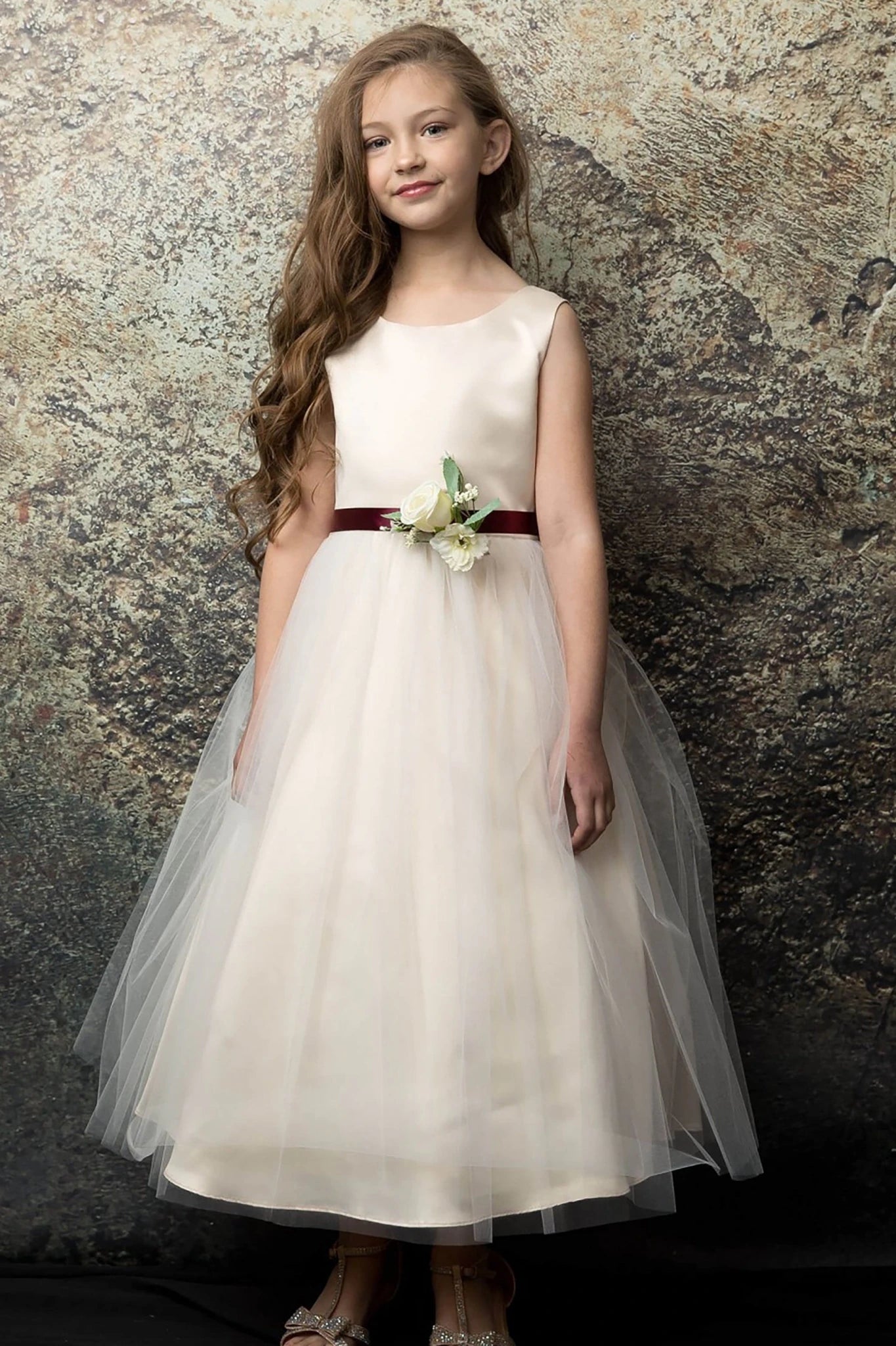 A champagne flower girl dress with a red belt.