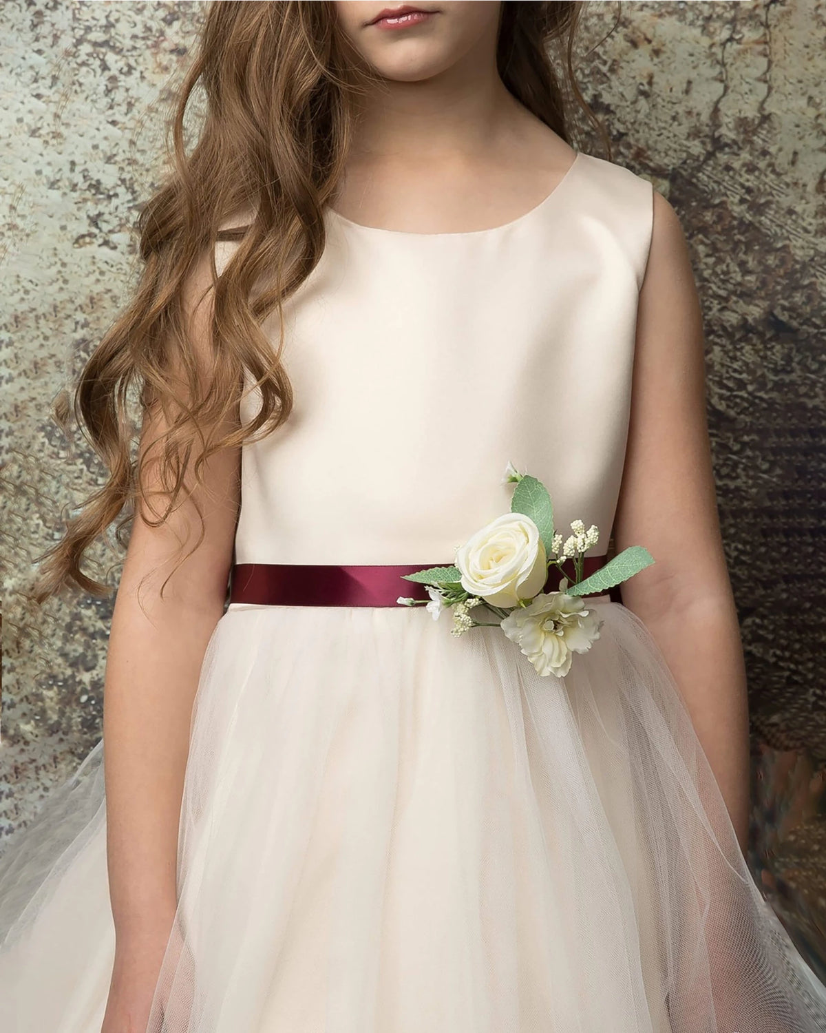 A champagne flower girl dress with a floral burgundy sash.