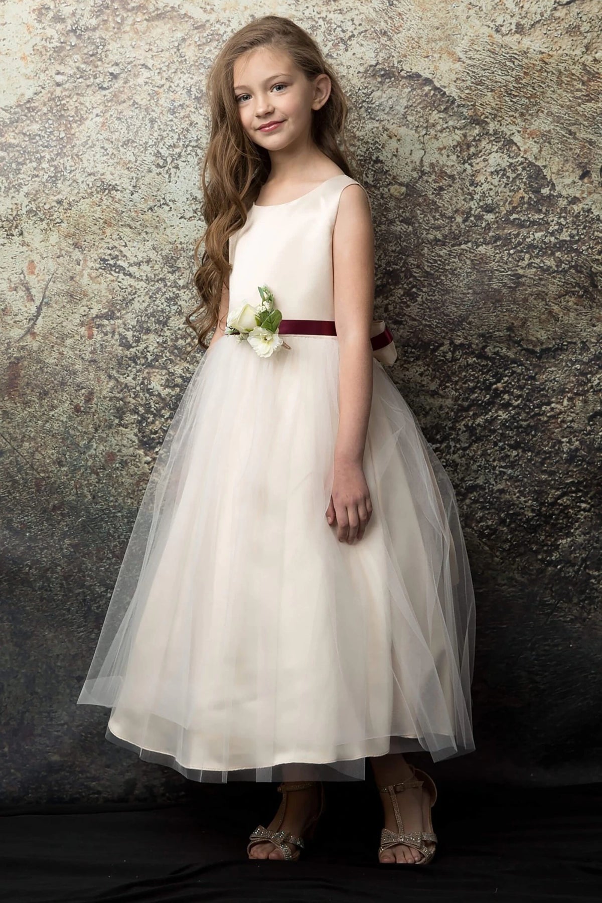 A champagne flower girl dress with a burgundy belt.